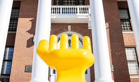 A yellow hand sculpture outside of Boyden Hall